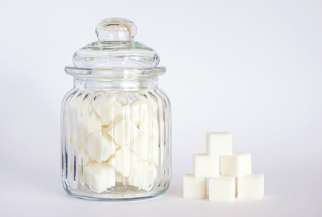 Bocal en verre rempli de morceaux de sucre et cubes empilés, symbole de l’addiction au sucre et du grignotage émotionnel