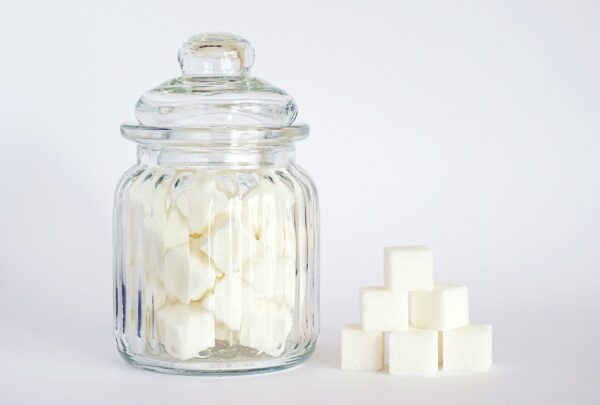 Bocal en verre rempli de morceaux de sucre et cubes empilés, symbole de l’addiction au sucre et du grignotage émotionnel