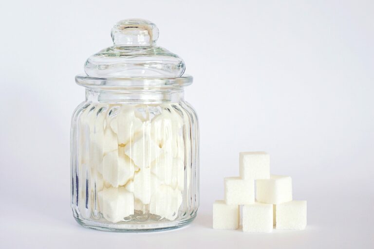 Bocal en verre rempli de morceaux de sucre et cubes empilés, symbole de l’addiction au sucre et du grignotage émotionnel