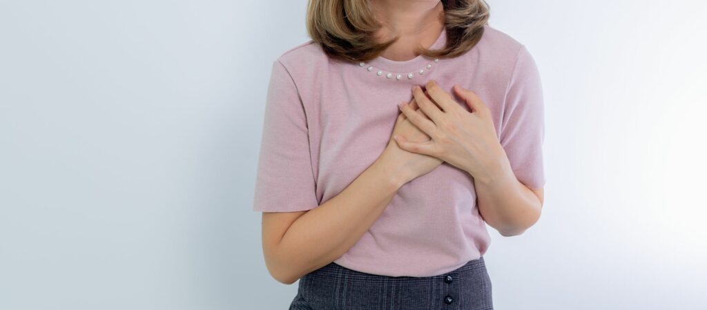 Femme les mains posées sur la poitrine, geste de bienveillance face à la culpabilité chronique