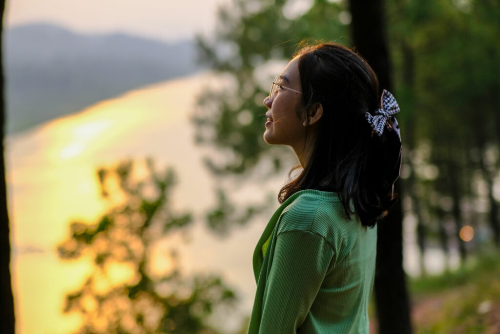 Femme de profil qui regarde l’eau au coucher du soleil, image de recul et d’apaisement après une rupture ou un deuil